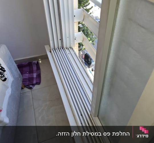 תריסים לבנים פתוחים על מסילה ליד חלון